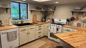 Kitchen featuring white cabinets, sink, white appliances, butcher block countertops, and light hardwood / wood-style floors