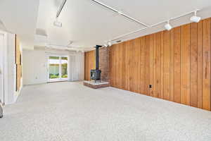 Family room with track lighting, wood walls, and fireplace