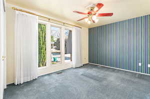 Spare room featuring plenty of natural light, ceiling fan, and carpet flooring