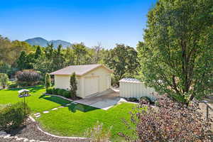 View of rear of property featuring a mountain view, work area, a shed, and a garage