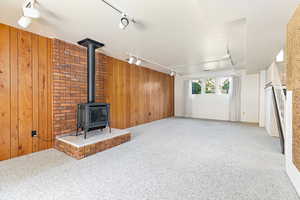 Family room featuring rail lighting, carpet flooring, a fireplace, and wooden walls