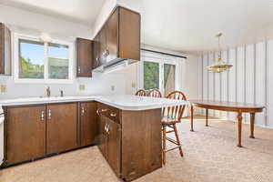 Kitchen featuring a textured ceiling, decorative light fixtures, kitchen peninsula, a breakfast bar area