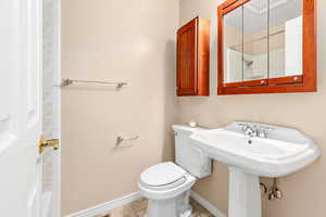 Bathroom with toilet, walk in shower, and tile patterned flooring