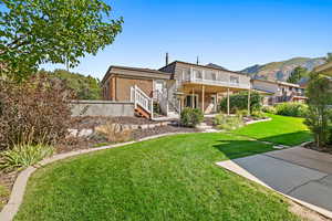 Rear view of house with a deck with mountain view, a yard, and a patio