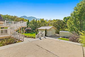 View of back of property with a work garage, a deck with mountain view, a storage shed