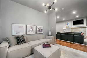 Living room with a fireplace, a chandelier, and light hardwood / wood-style floors