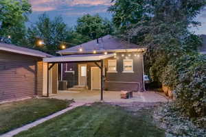 Back house at dusk with a patio area, a yard, and central air condition unit