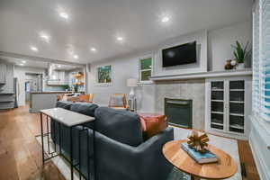 Living room with light wood-type flooring and a tile fireplace