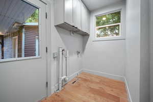 Laundry room with cabinets, hookup for an electric dryer, and light hardwood / wood-style floors