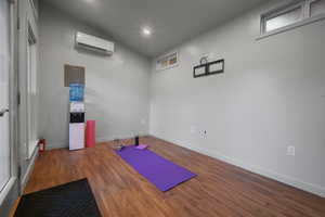 Exercise room with lofted ceiling, hardwood / wood-style floors, and a wall mounted air conditioner