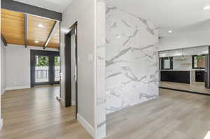 Corridor with wood ceiling, vaulted ceiling, and light hardwood / wood-style flooring