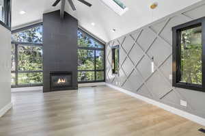 Unfurnished living room featuring a healthy amount of sunlight, ceiling fan, light hardwood / wood-style flooring, and a fireplace