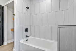 Bathroom with tiled shower / bath and wood-type flooring