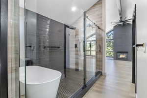 Bathroom with a fireplace, lofted ceiling, independent shower and bath, and ceiling fan