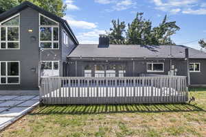 Rear view of house featuring a deck and a lawn