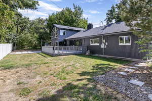 Back of property featuring a deck and a lawn