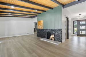 Unfurnished living room featuring light hardwood / wood-style floors, wooden ceiling, and beam ceiling