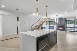 Kitchen with black microwave, a center island, a fireplace, and light wood-type flooring