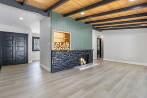 Unfurnished living room featuring wooden ceiling, light hardwood / wood-style flooring, and beam ceiling