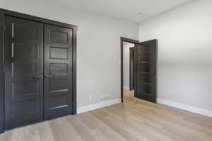 Unfurnished bedroom with light wood-type flooring and a closet