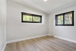 Unfurnished room featuring vaulted ceiling and light hardwood / wood-style flooring