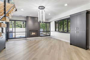 Unfurnished living room with light wood-type flooring, a large fireplace, and a textured ceiling