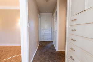 Hallway featuring dark colored carpet