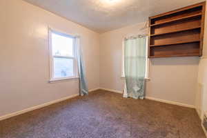 Carpeted empty room featuring a textured ceiling