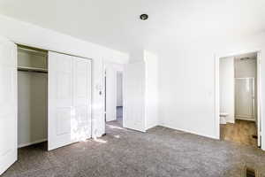 Unfurnished bedroom with carpet floors, a textured ceiling, a closet, and ensuite bath