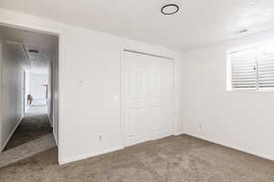 Unfurnished bedroom featuring a textured ceiling, carpet flooring, and a closet