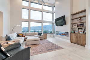 Living room with built in shelves, a healthy amount of sunlight, ceiling fan, and a high ceiling