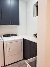 Laundry area featuring washing machine and clothes dryer and cabinets