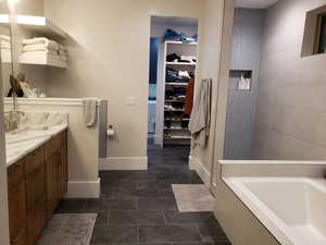 Bathroom with a tub to relax in, vanity, and tile patterned floors