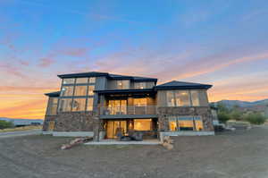 Back house at dusk with a balcony, a patio area, and a mountain view