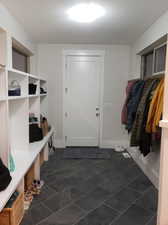 Mudroom with dark tile patterned flooring and a textured ceiling