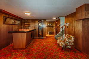 Bar featuring dark carpet and wooden walls