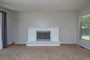 Unfurnished living room with light colored carpet and a brick fireplace