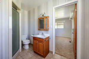 Bathroom featuring tile patterned flooring, vanity, toilet, and a shower with shower door