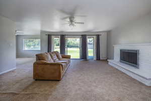 Carpeted living room with a fireplace and ceiling fan