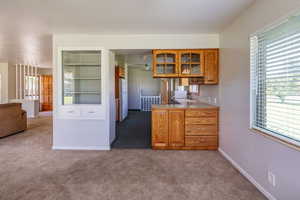 Kitchen featuring kitchen peninsula, white fridge, sink, and carpet floors