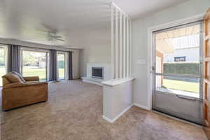 Living room featuring ceiling fan, light carpet, and a brick fireplace