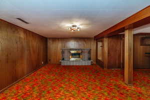 Basement featuring dark colored carpet and wooden walls