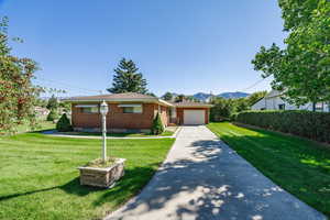 View of front facade with a mountain view, a garage, and a front yard