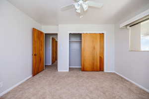 Unfurnished bedroom featuring a closet, ceiling fan, and light carpet