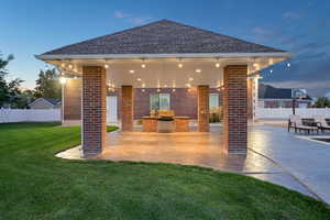 Back house at dusk with a yard and a pavillion patio