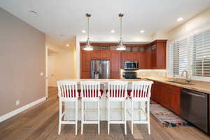 Kitchen featuring pendant lighting, sink, a kitchen island, appliances with stainless steel finishes, and dark hardwood / wood-style floors