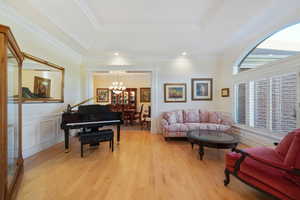 Living room with a raised ceiling, crown molding, and light hardwood / wood-style flooring