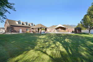 Rear view of house with a lawn, a gazebo, a patio, and a shed