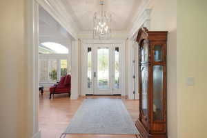 Foyer with an inviting chandelier, crown molding, and light hardwood / wood-style floors