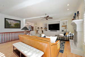 Family room with ceiling fan, light wood-type flooring, a fireplace, and ornamental molding